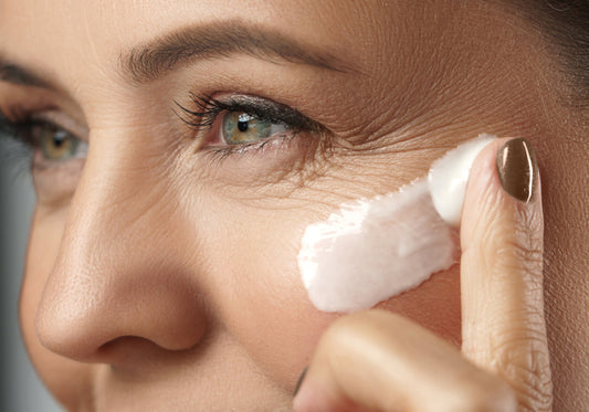 Close up shot of an elderly woman applying botox-like peptide on her face with a finger. anti-age cream, firm skin, elasticity