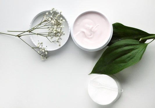 organic skin care. an open container of organic face cream with plants next to them